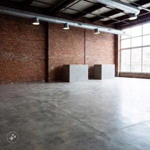 Minimalist brutalist interior design featuring raw concrete walls, exposed structural elements, and simple, functional furniture with clean lines, creating an industrial yet modern aesthetic.