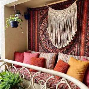 A modern home balcony design featuring a cozy seating area with cushioned chairs and a small coffee table, surrounded by lush green plants and soft ambient lighting