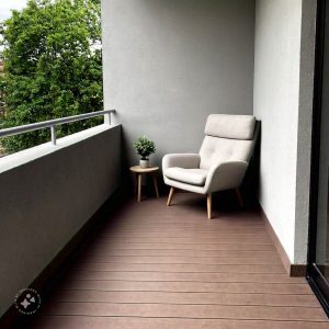 A modern home balcony design featuring a cozy seating area with cushioned chairs and a small coffee table, surrounded by lush green plants and soft ambient lighting, creating a relaxing outdoor retreat