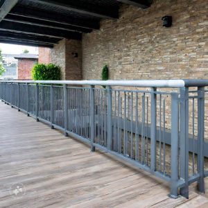 A modern home balcony design featuring a cozy seating area with cushioned chairs and a small coffee table, surrounded by lush green plants and soft ambient lighting, creating a relaxing outdoor retreat