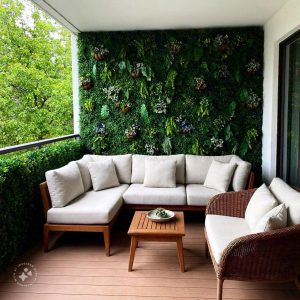 A modern home balcony design featuring a cozy seating area with cushioned chairs and a small coffee table, surrounded by lush green plants and soft ambient lighting, creating a relaxing outdoor retreat