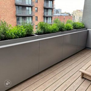 A modern home balcony design featuring a cozy seating area with cushioned chairs and a small coffee table, surrounded by lush green plants and soft ambient lighting, creating a relaxing outdoor retreat