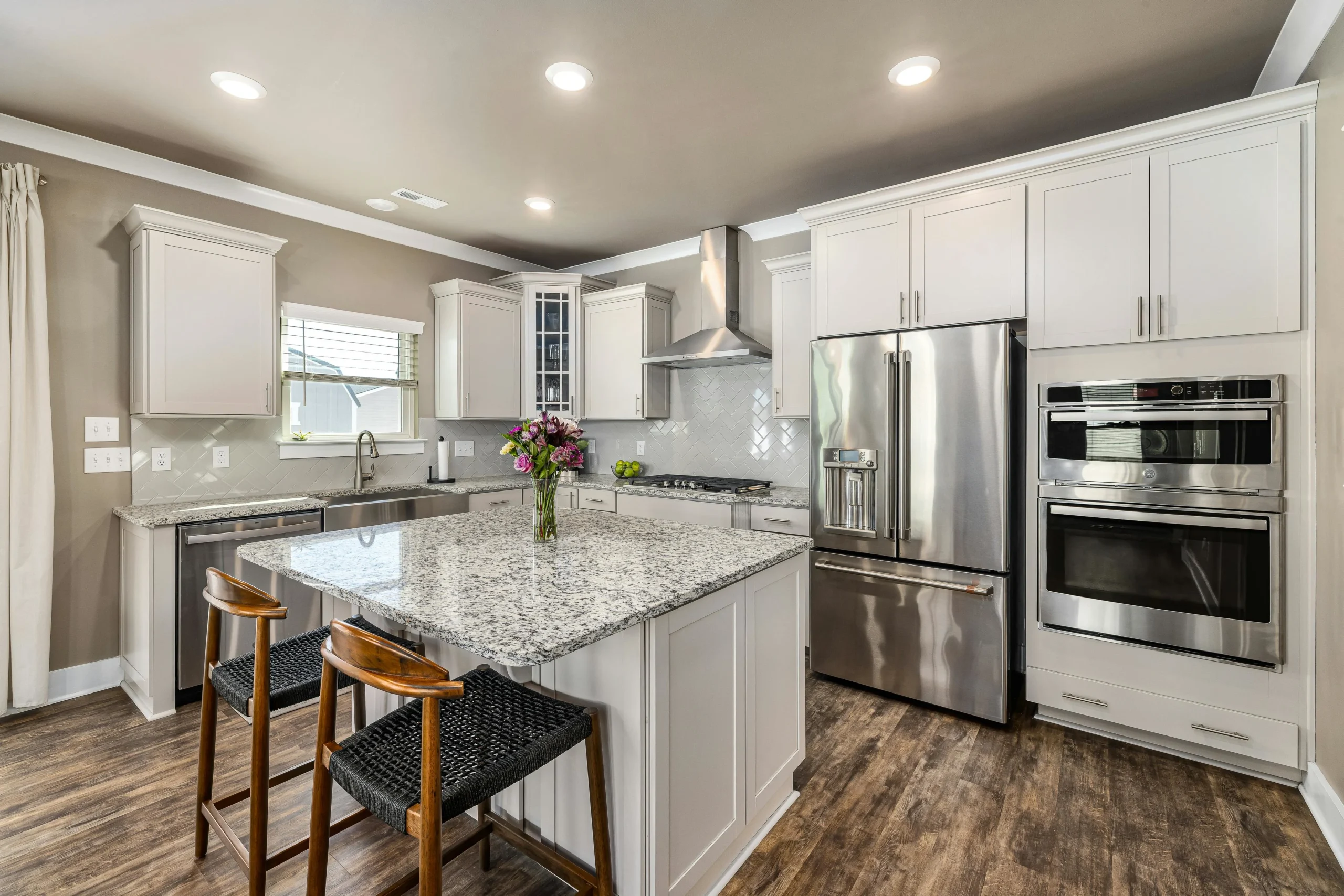 Modern L-shaped kitchen with white cabinets and granite countertops.