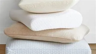  Stacked pillows with varied textures, neutral colors.