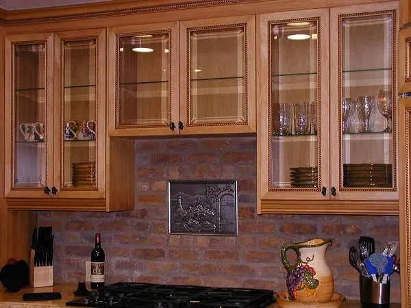 Traditional kitchen design featuring wooden cabinetry with glass-paneled doors, a brick backsplash, and a built-in gas stove.