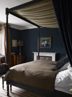 Dark cozy bedroom with canopy bed, blue walls, and wood decor