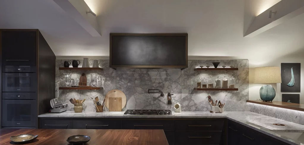 Luxury dark-toned kitchen with marble backsplash and wood accents.