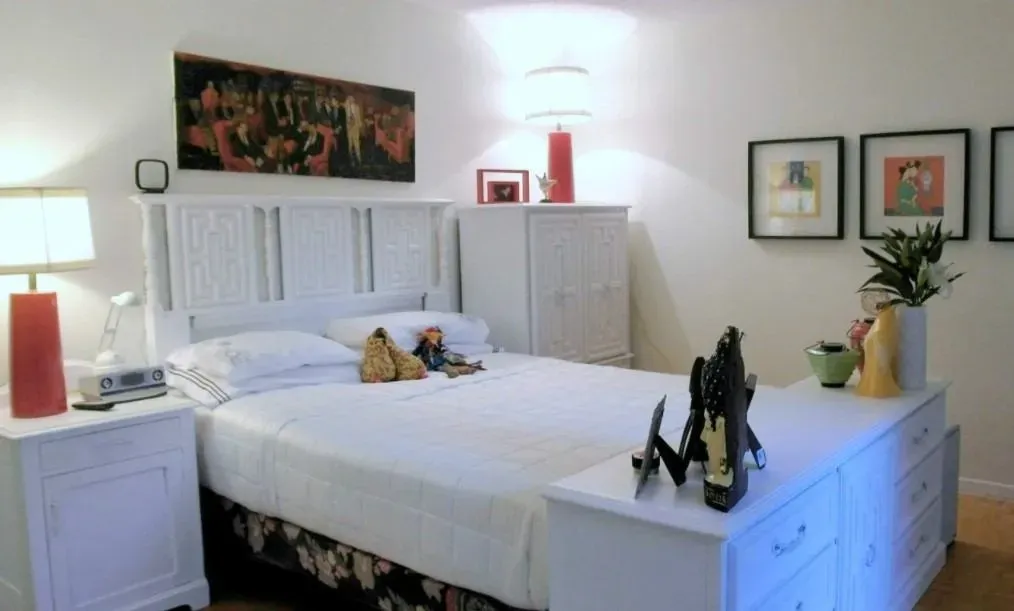 Contemporary bedroom with white furniture and red accents.