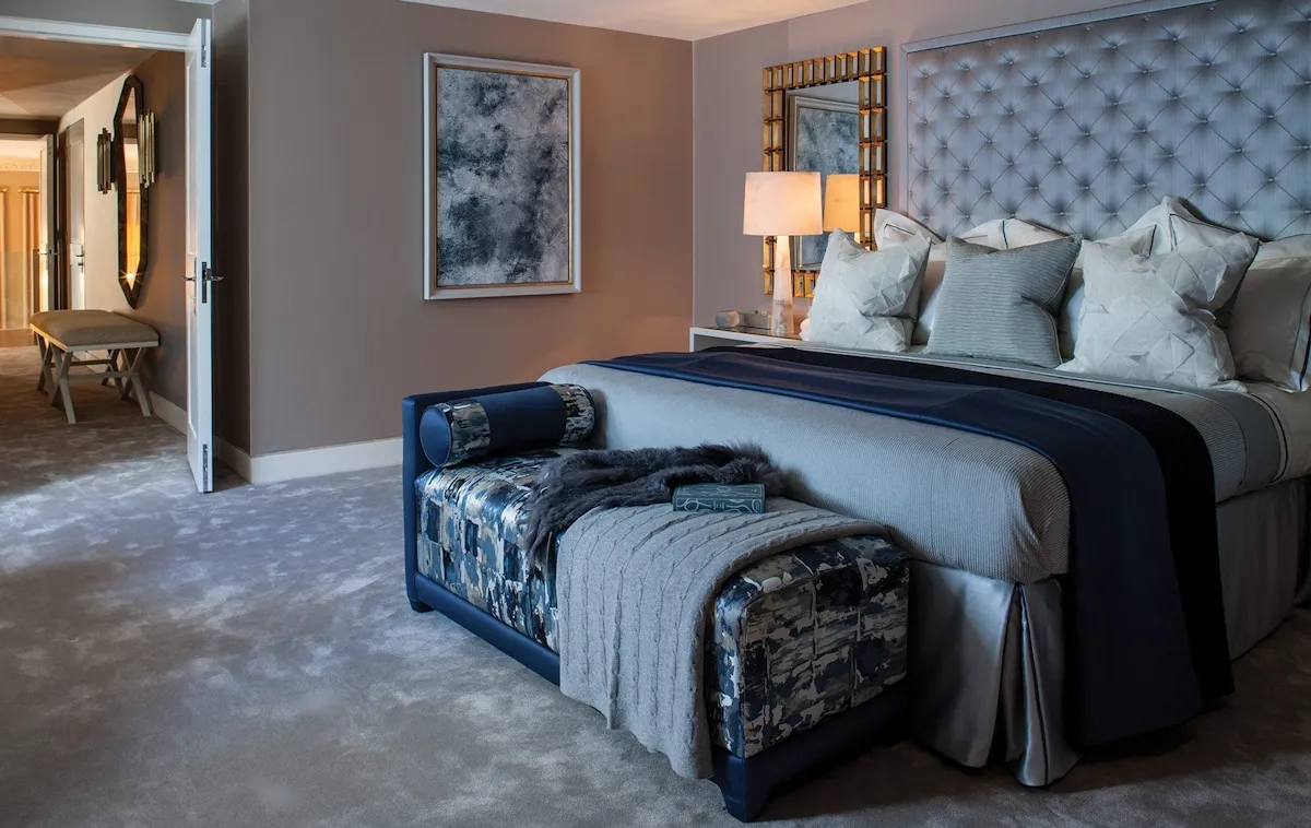 Cozy bedroom with blue-gray walls, tufted headboard, and bench