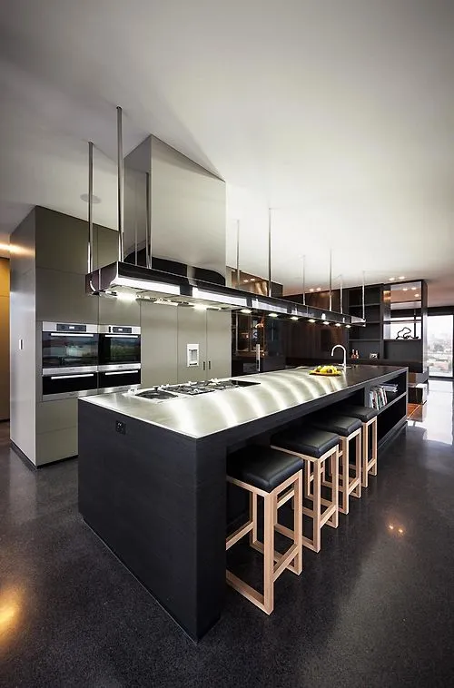 Modern kitchen island, stools, stainless steel, cabinets, lighting.