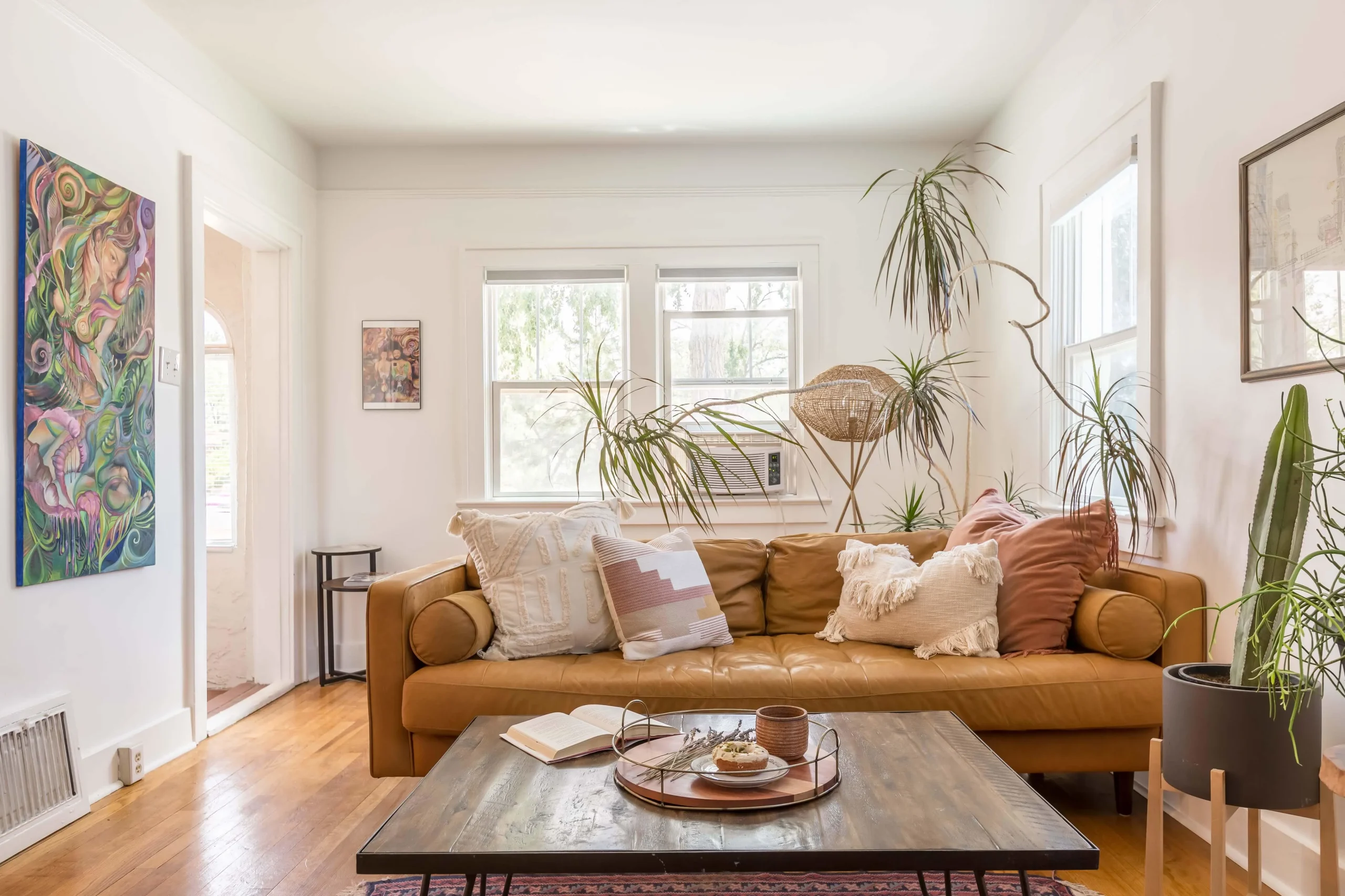 Small living room tan sofa plants and wood table.